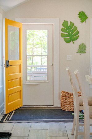 A room with a yellow door, a window, a doormat, a wicker basket, and a wooden chair. - Laid-back, luxurious 4-bed, 2-bath home, 10-minute walk to downtown Saugatuck (Saugatuck)