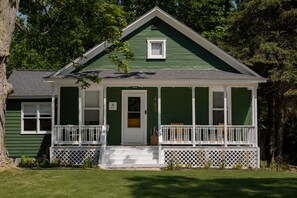 A green house with a white porch, a front door, and a mailbox. - Laid-back, luxurious 4-bed, 2-bath home, 10-minute walk to downtown Saugatuck (Saugatuck)
