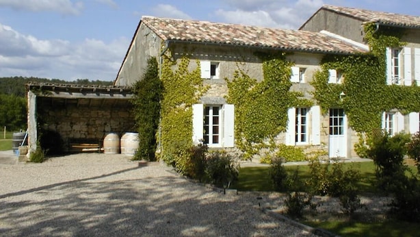 A stone building with a tiled roof, white shutters, and a gravel driveway. - Petit Gite de la Mondette (LES-SALLES-DE-CASTILLON)