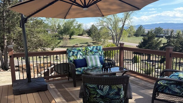 Una terraza con mobiliario de mimbre, un parasol grande y vistas al paisaje.