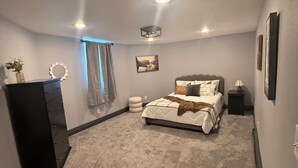 Un dormitorio con cama, cómoda y una mesita.