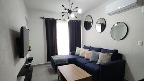 A modern living room with a sofa, coffee table, mounted TV, and a ceiling light fixture. - Perfect 2-bedroom apartment with AC in lovely Acapulco de Juárez (Acapulco de Juárez)