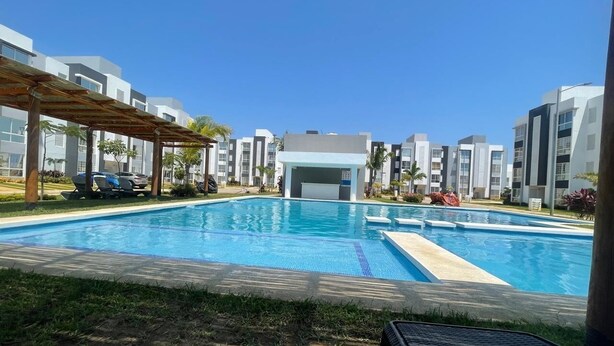 A swimming pool with a wooden pergola, surrounded by modern buildings and a clear sky. - Perfect 2-bedroom apartment with AC in lovely Acapulco de Juárez (Acapulco de Juárez)