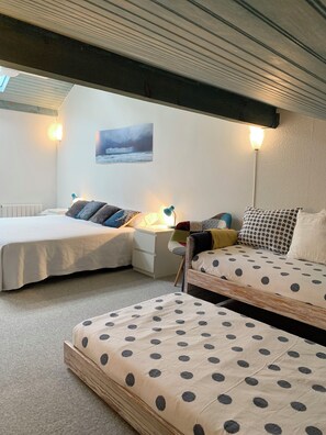 Ein Zimmer mit zwei Betten, einem Nachttisch, einer Lampe, einem Wandbild und einer Decke mit freiliegenden Balken.