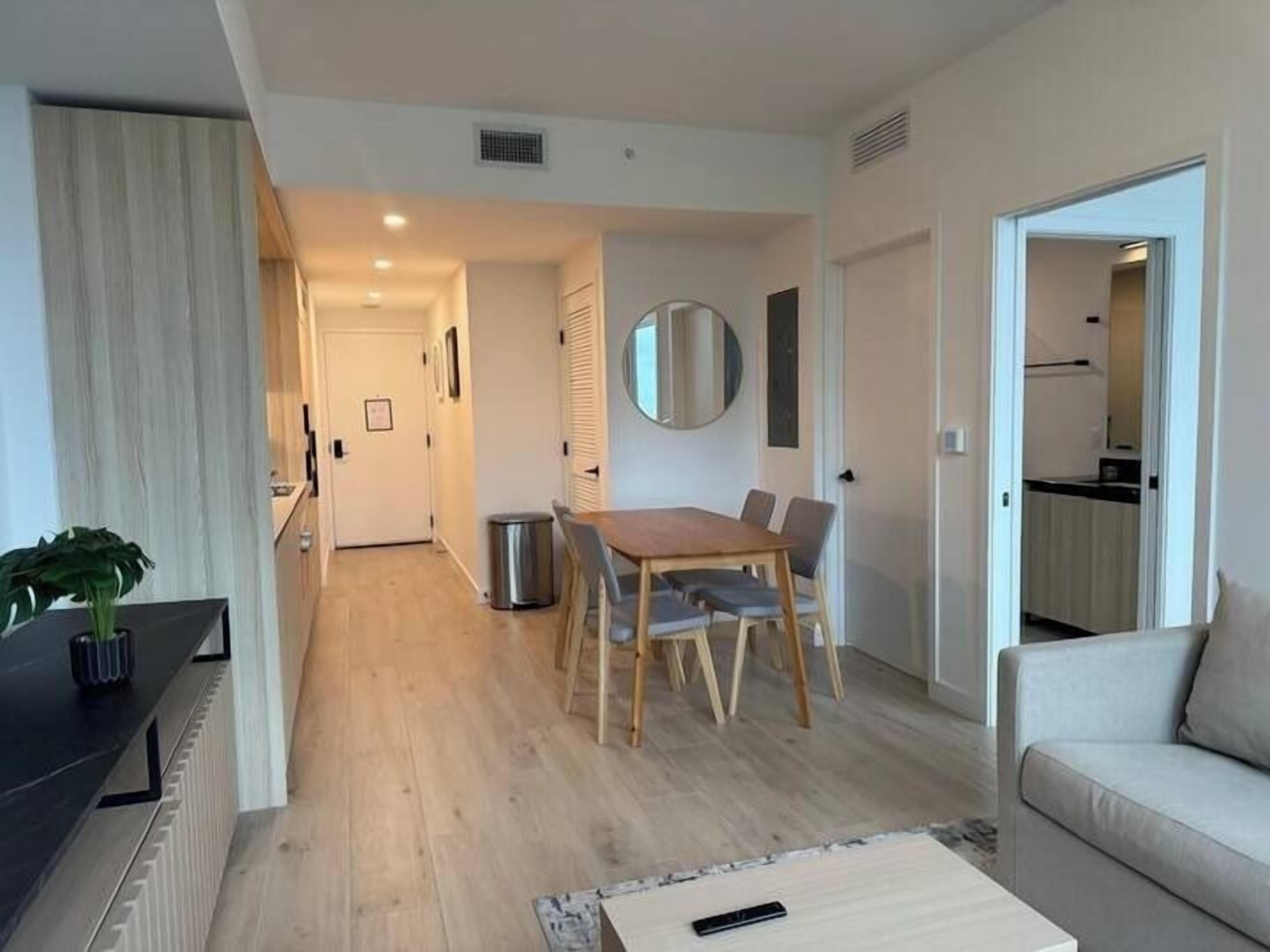 Un salon moderne comprenant un coin repas, un canapé, une table basse et une plante.
