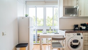 Una cocina funcional con microondas, lavadora y una mesa con sillas.