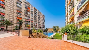 Edificio residencial con varios balcones, piscina y jardín bien cuidado.