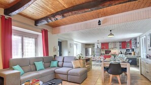 Una sala de estar con un sofá, una mesa de comedor con sillas y una cocina con armarios rojos.