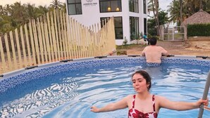 Ein Schwimmbad mit Holzzaun und einem Gebäude im Hintergrund, auf dem 'JARDIN DEL MAR REAL ESTATE' steht.