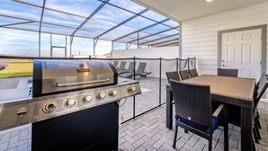 Un porxo cobert amb una barbacoa, mobles d'exterior i vista al cel.