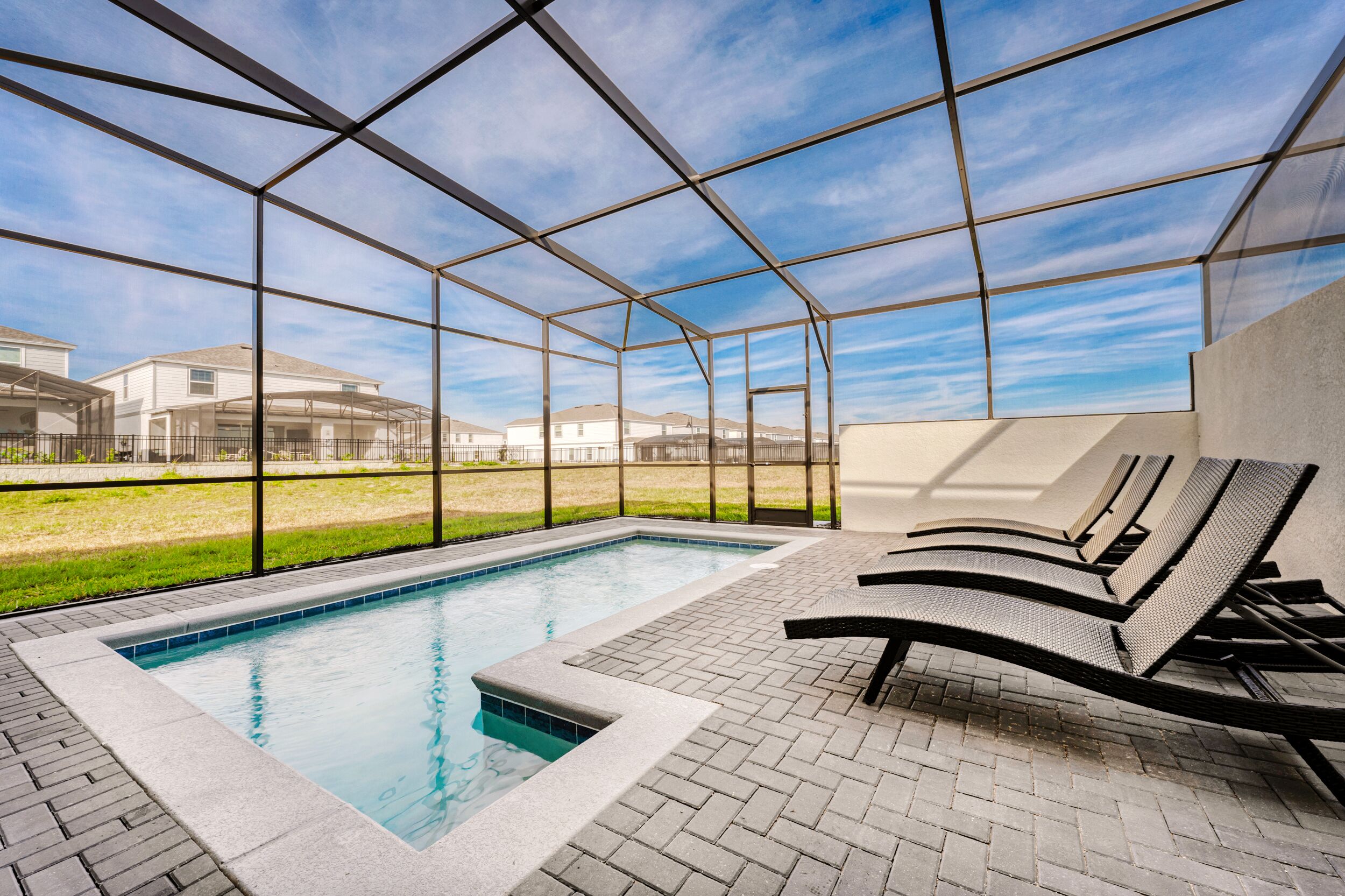 Zona de piscina con una vista despejada del cielo, una pileta y sillones de descanso.