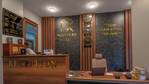 Un comptoir d’accueil avec un revêtement en bois, une horloge murale et un panneau indiquant les services disponibles, tels qu’un restaurant et un service de petit-déjeuner.