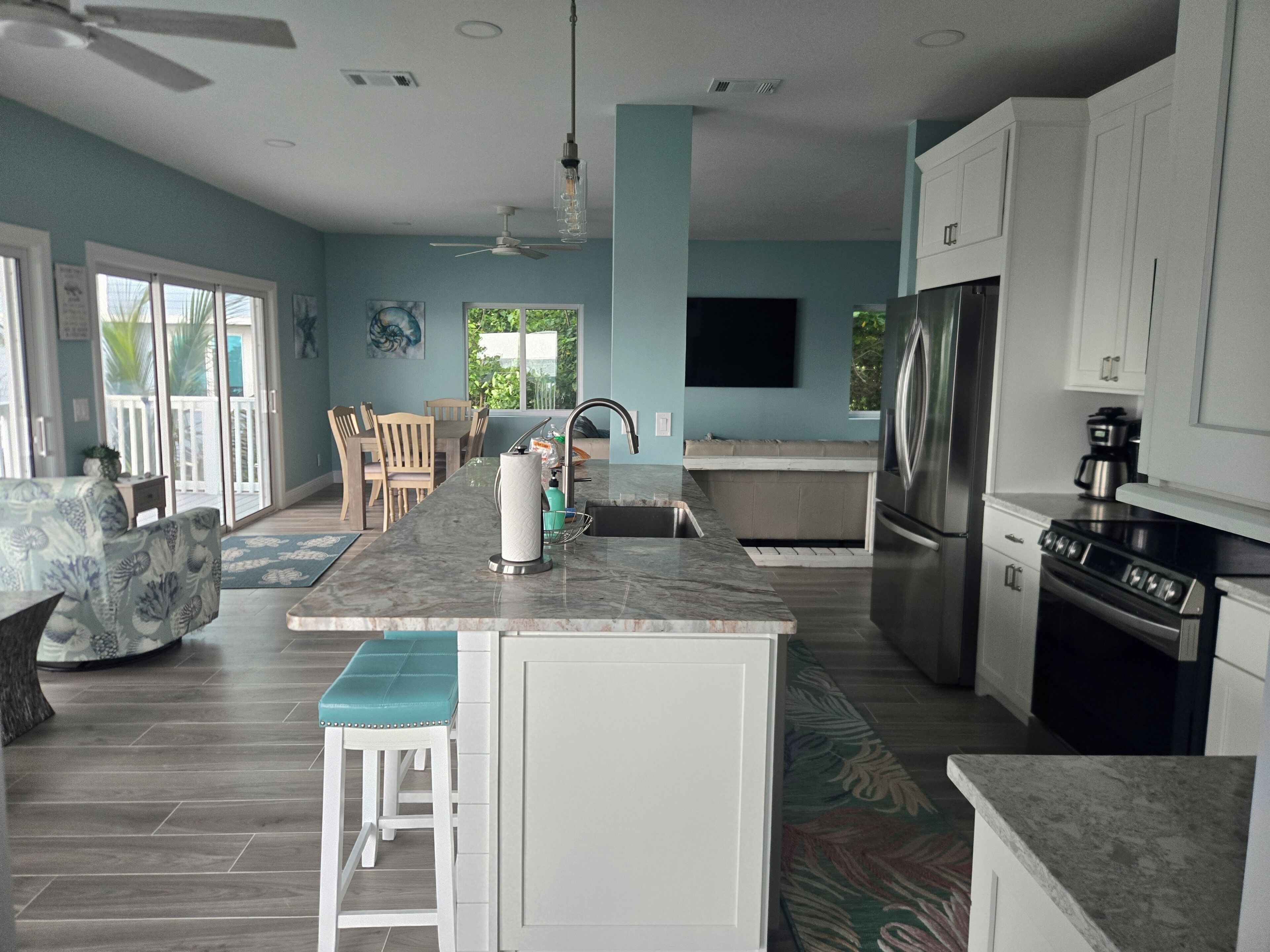 A modern kitchen with a central island, stainless steel appliances, and a dining area with a view.