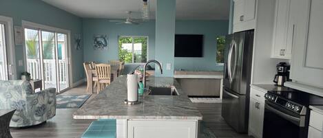 A modern kitchen with a central island, stainless steel appliances, and a dining area with a view.
