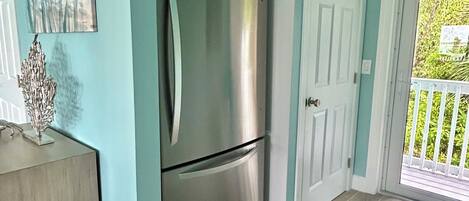 A kitchen with a stainless steel refrigerator, a wooden cabinet, and a door leading to a balcony.