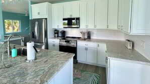 A modern kitchen with white cabinets, stainless steel appliances, and a granite countertop. - Beachfront Secluded Sunset Sanctuary with Panoramic Views (Captiva)