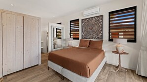 Une chambre à coucher comprenant un lit, une armoire, un élément décoratif mural et une fenêtre avec des stores.