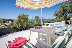 Een terras met een tafel, stoelen en een gestreepte parasol.