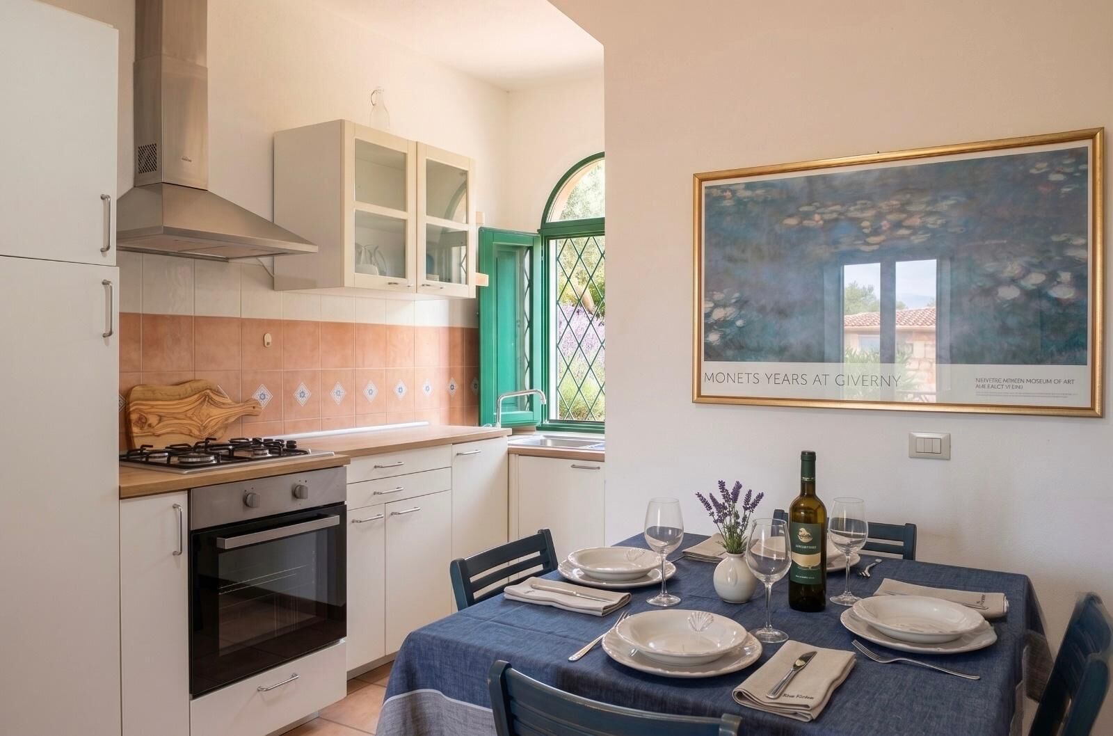 Een keuken met een eethoek, een kookplaat, oven, kastjes en een gedekte tafel.