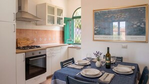 A kitchen with a dining area, a stove, oven, cabinets, and a table set for dining. - Acqua del Mare | Welcomely (Tanaunella)