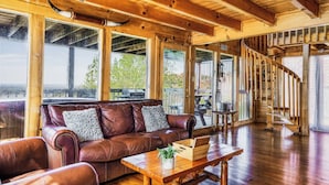 A wooden interior with a leather sofa, wooden table, and a spiral staircase. - Panoramic Views w/ Hot Tub, Pool Table, Arcade! (Sevierville)