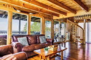 A wooden interior with a leather sofa, wooden table, and a spiral staircase. - Panoramic Views w/ Hot Tub, Pool Table, Arcade! (Sevierville)