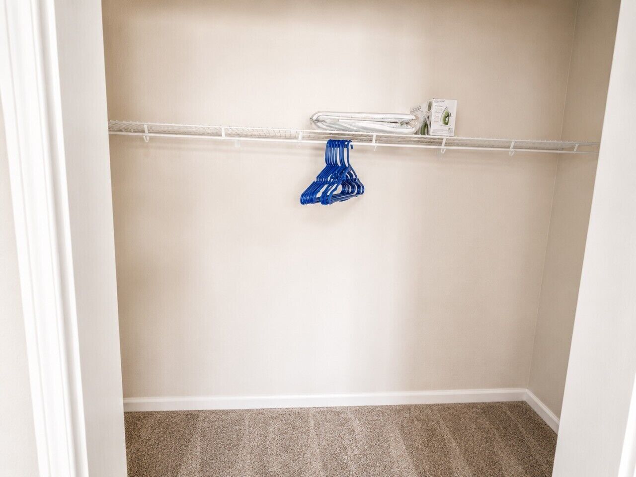 Een hoekkast met een beigekleurige muur, een witte deurpost en een vloerbedekt met tapijt.