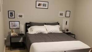 A bedroom with a bed, two bedside tables, a nightstand, a lamp, framed pictures on the wall, and a ceiling light. - Private DC Apartment - 1BR - Walk to Metro - Explore Washington DC (Washington)