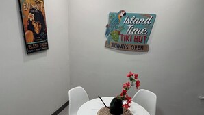Ett konferensrum med ett runt bord, vita stolar, en dekorativ skylt och en affisch på väggen.