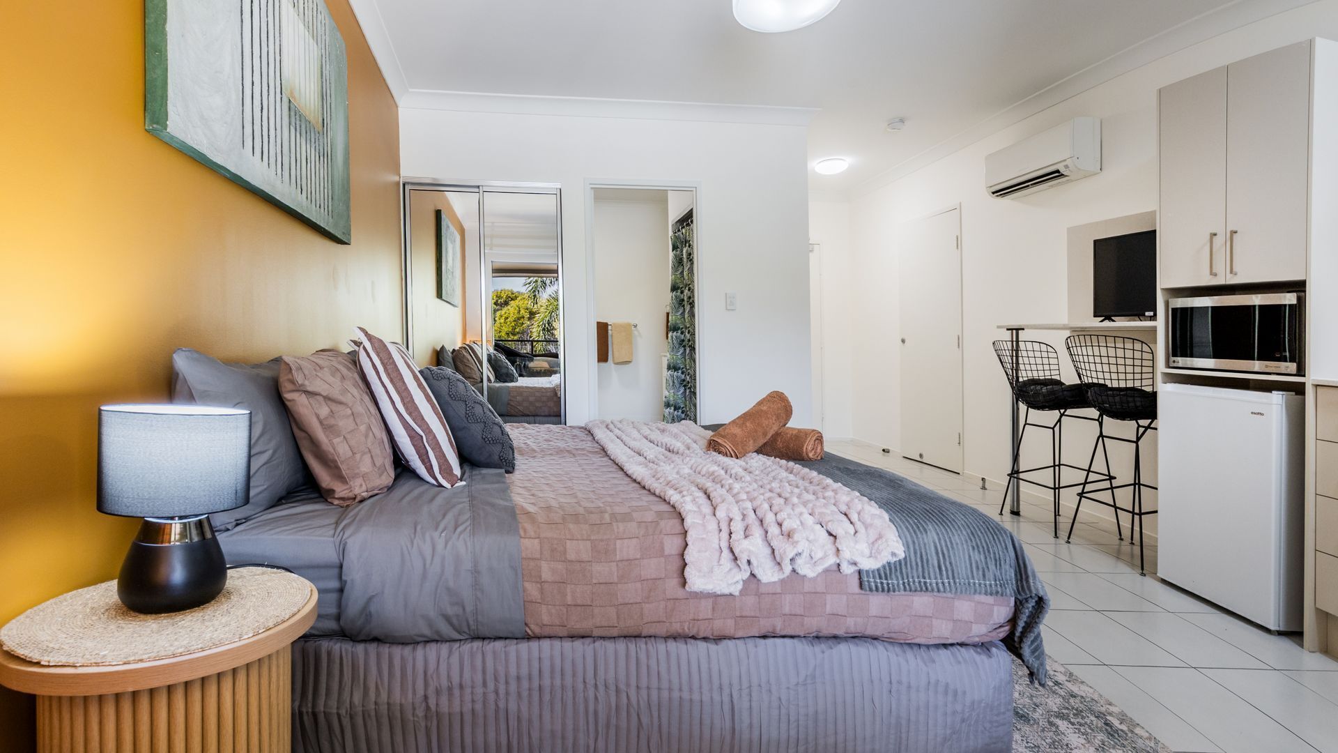 Un dormitorio moderno con cama, mesita de noche y vistas al baño contiguo.