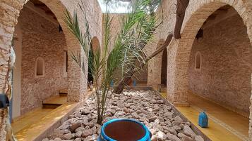 An interior courtyard with stone arches, a central water feature, and a blue pot on a table.