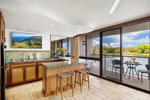 Een moderne keuken met een groot kookeiland, houten kastjes en uitzicht op een bergachtig landschap door grote ramen.