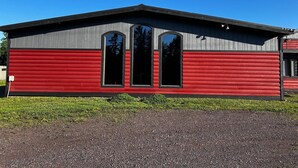 En rød og grå bygning med tre store vinduer og et fladt tag.