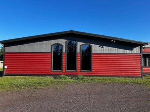 Ein rotes und graues Gebäude mit drei großen Fenstern und einem flachen Dach.