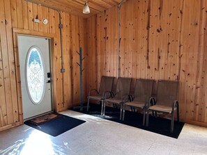 A room with wooden walls, a door with a stained glass window, and a bench seating area. - North Shore Den on 61 (Two Harbors)