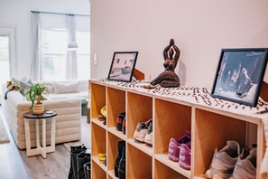 Een woonkamer met een houten plank waarop schoenen staan en een kleine tafel met een plant.