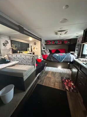 Ein kompaktes Wohnmobil-Interieur mit Bett, Küchenzeile und einer kleinen Sitzecke.