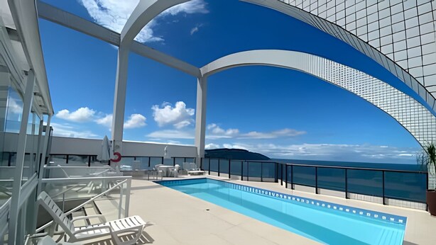 Zona de piscina con sillones de descanso y vista despejada al océano.