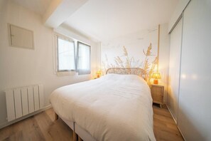 Ein Schlafzimmer mit einem großen Bett, einem Fenster, einer Heizung und einer Wand mit Pflanzenmuster.