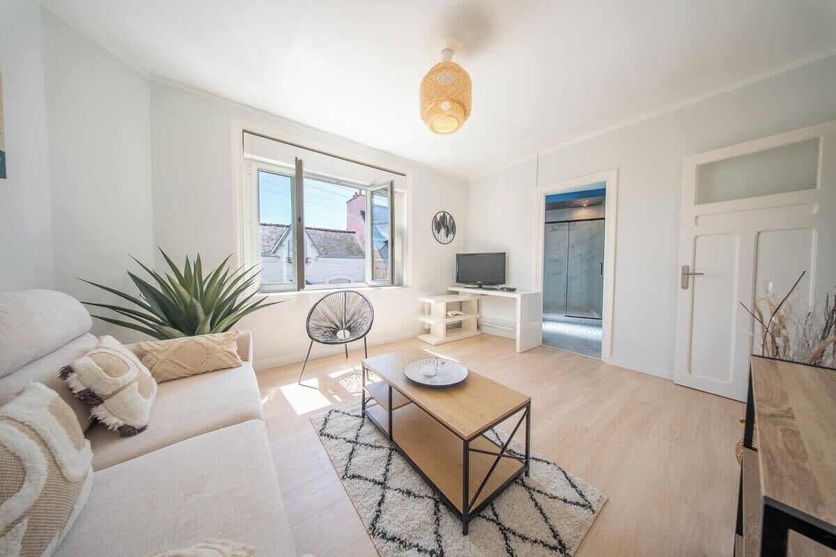 Un salon moderne avec un canapé, une table basse, un téléviseur et une grande fenêtre.