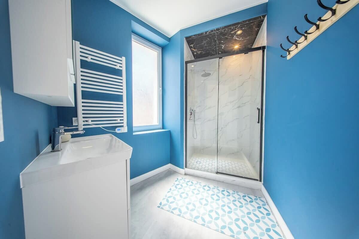 Une salle de bain avec une douche, un lavabo et une fenêtre.
