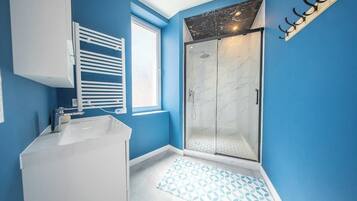Une salle de bain avec une douche, un lavabo et une fenêtre.