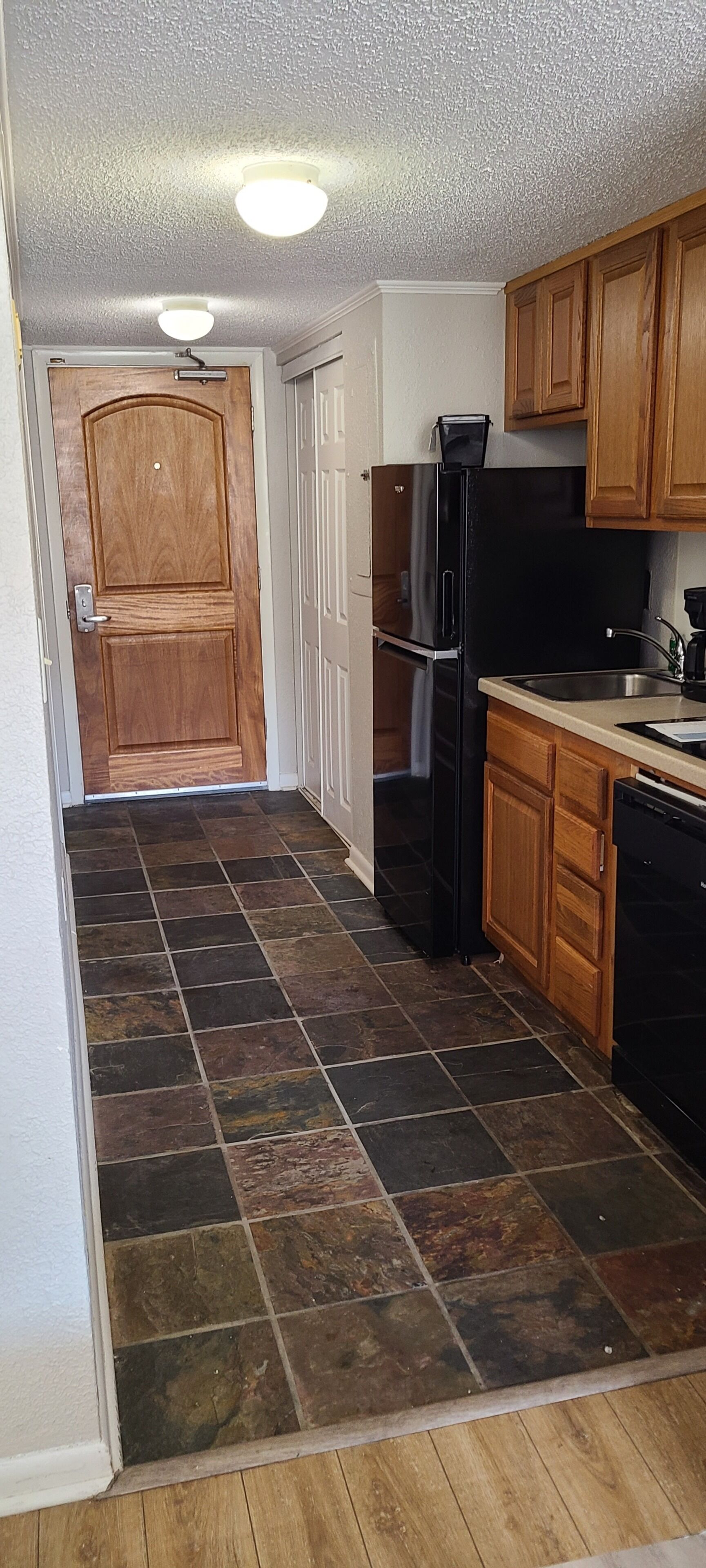 A kitchen with a refrigerator, dishwasher, and wooden cabinets.