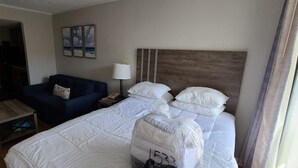 Habitación de hotel con cama, sofá, mesita de noche, lámpara y un cuadro en la pared.