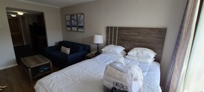 Et hotelværelse med seng, sofa, et natbord, en lampe og et billede på væggen.
