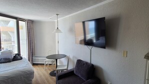 Habitación de hotel con cama, televisión montada en la pared, una mesita y una silla.