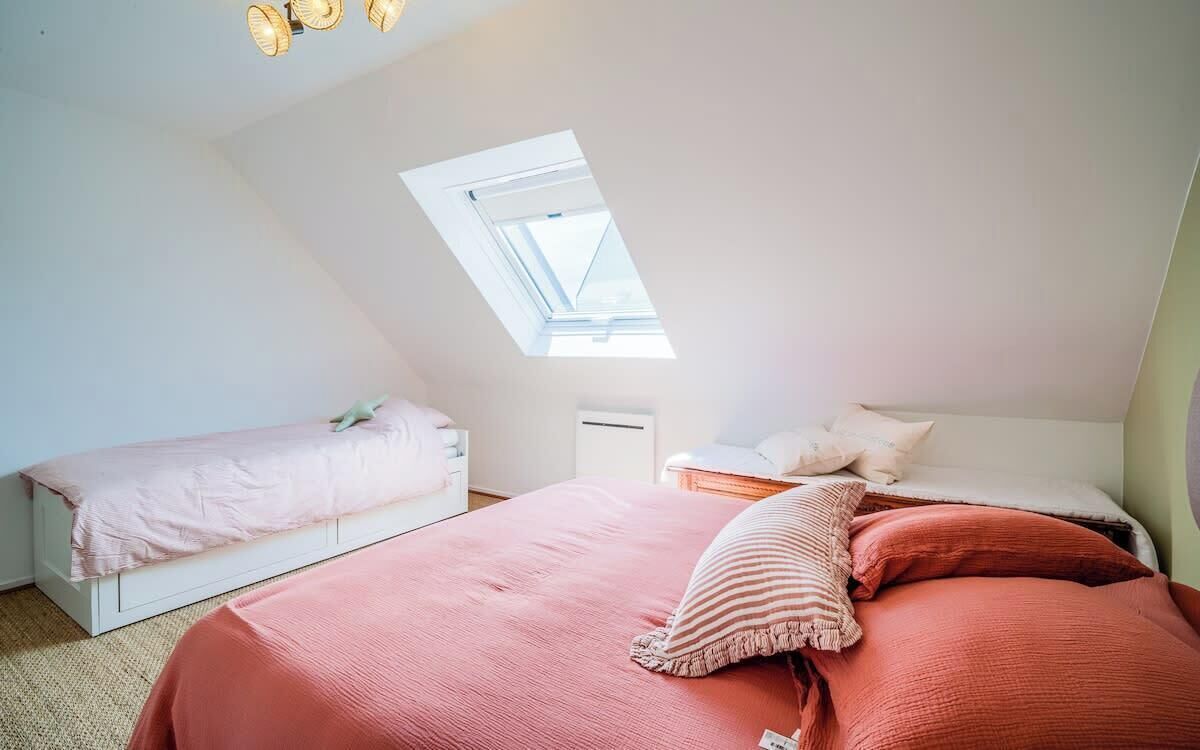 A bedroom with a skylight, two beds, and a small bedside table.