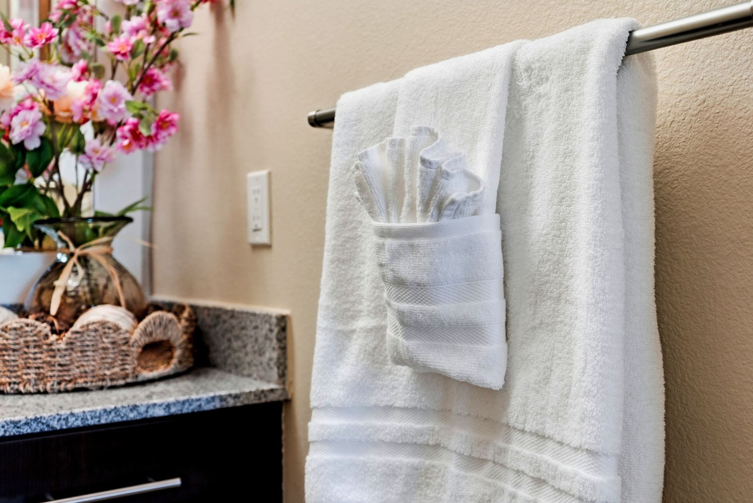 A bathroom with a towel rack holding a white towel and a folded towel.