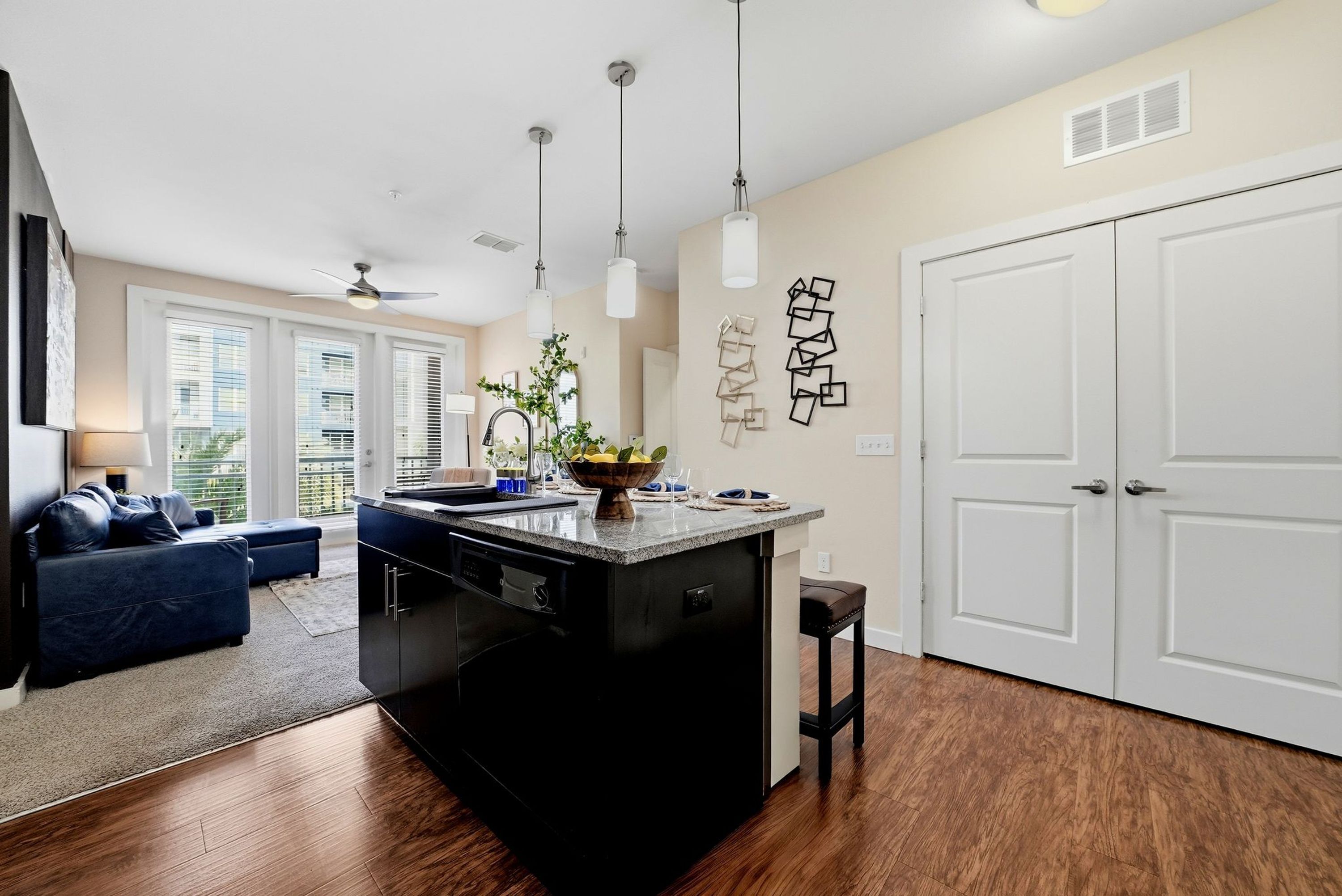A modern kitchen with a central island, pendant lights, and a view to a balcony.