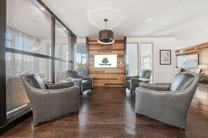 Een receptie met een logo, twee leren banken, een houten wand en een groot raam.